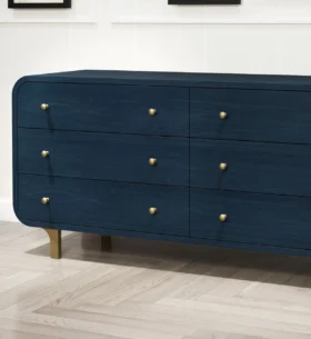 Dark blue wood dresser with brass hardware displayed in a showroom, highlighting the furniture's painted wood finish and clean, rounded edges.