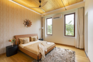 Bedroom with white walls, beige and golden accents, and bright wooden ceiling.