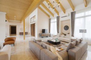 Living area with light grey sofas, white walls, exposed wooden beams and bright wooden ceiling.