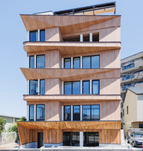 A mid-rise commercial building showcases the use of wood throughout columns, walls, balconies and roof.