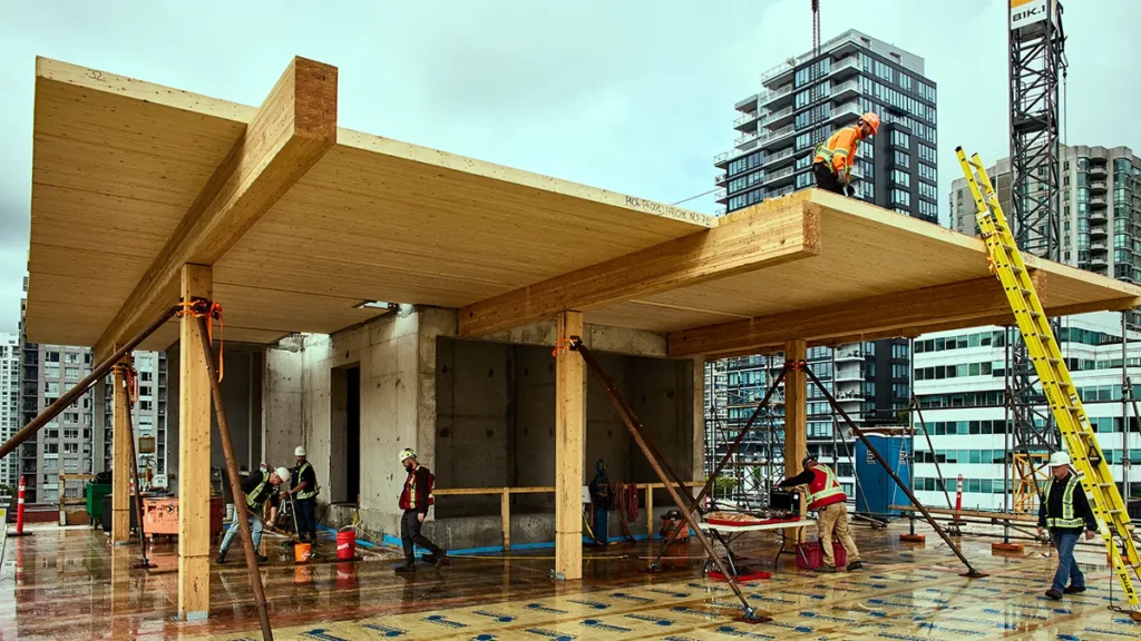 Exposed mass timber floor panels and glulam beams are installed on a mid-rise building under construction, highlighting the structural wood system during assembly.