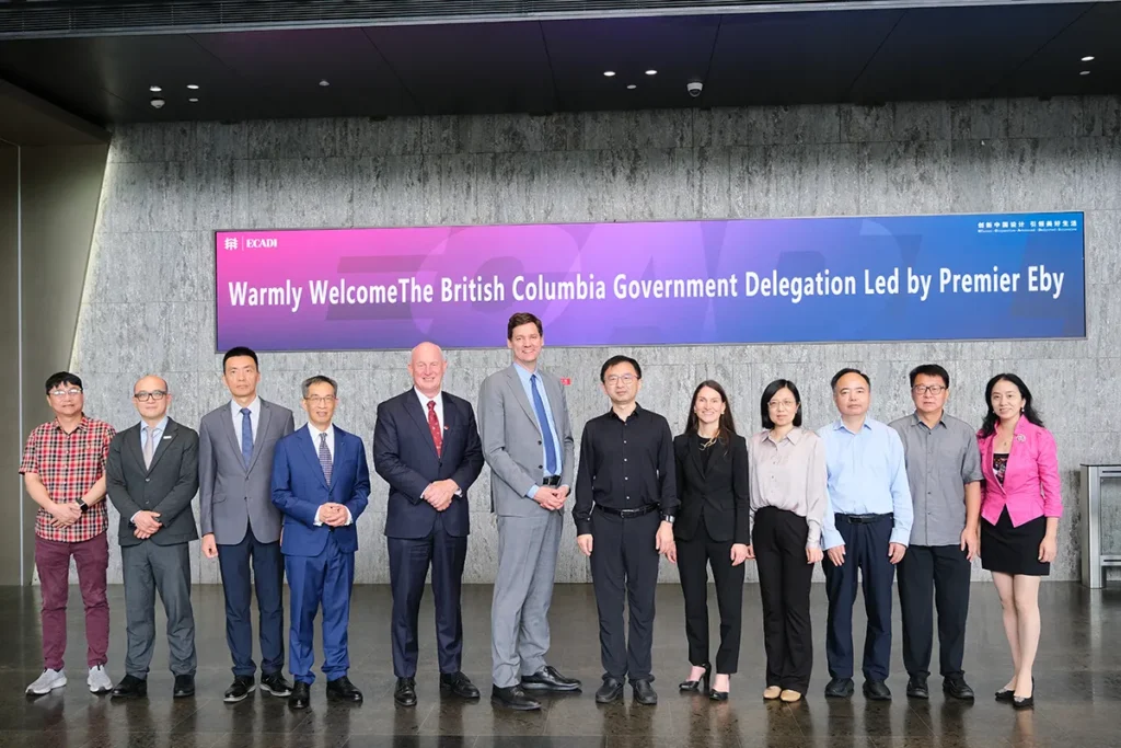 Premier David Eby, members of the British Columbia delegation and ECADI representatives pose for a group photo beneath a welcome sign recognizing the British Columbia government delegation.