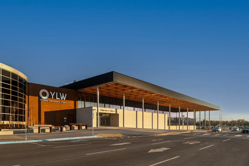 Kelowna International Airport terminal featuring an exposed mass timber roof canopy, showcasing wood construction across the building's expansive entrance structure.