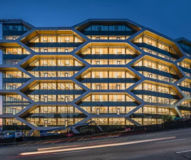 Office building with a distinctive geometric façade that highlights exposed mass timber structure and floor plates behind glass walls.