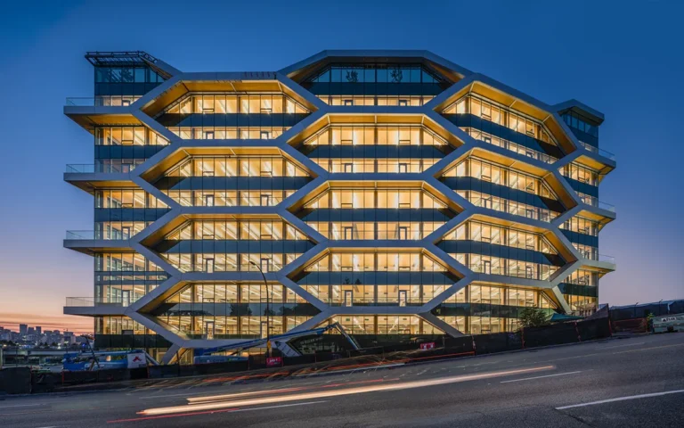 Office building with a distinctive geometric façade that highlights exposed mass timber structure and floor plates behind glass walls.