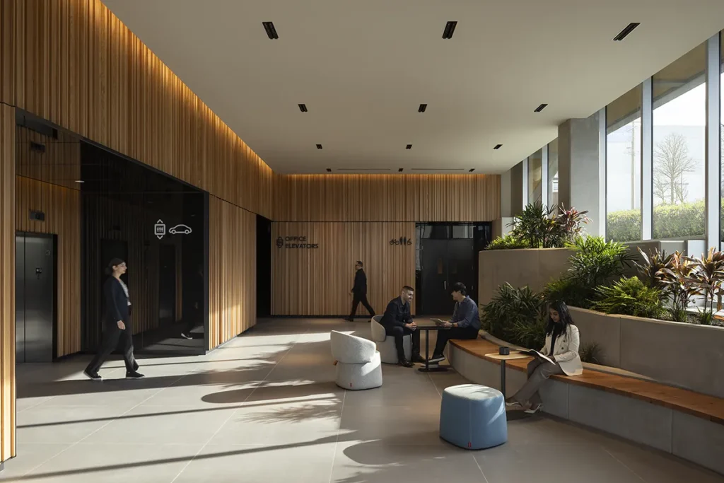 Lobby interior featuring floor-to-ceiling mass timber wall panels and integrated wood seating, highlighting the extensive use of exposed wood in a modern commercial building.
